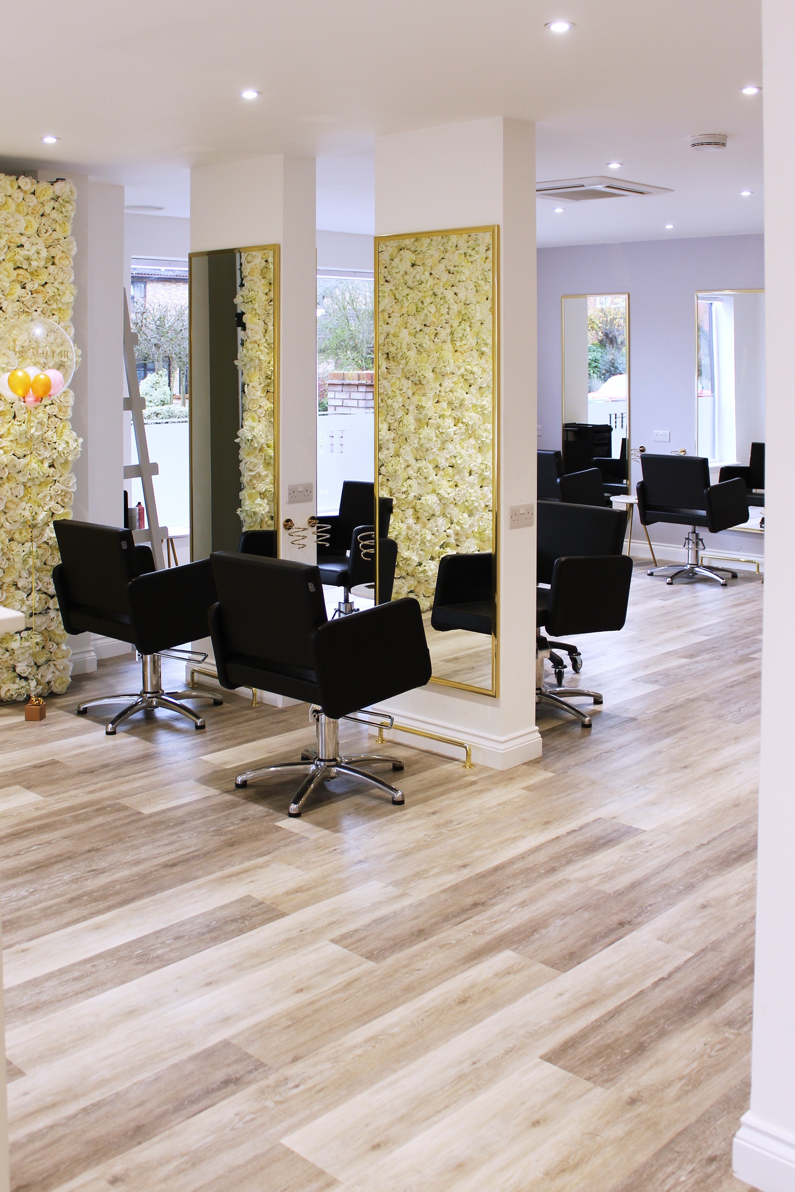 Styling stations with black chairs and flower wall mirrors